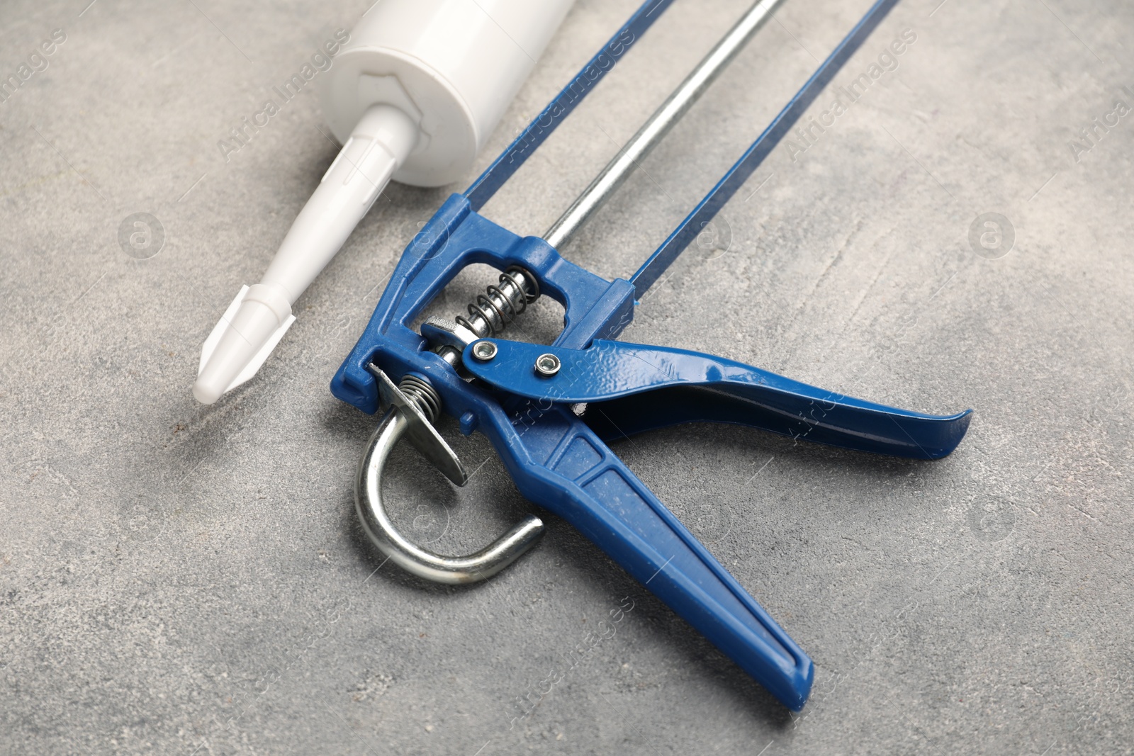 Photo of Glue gun and tube on grey background, closeup