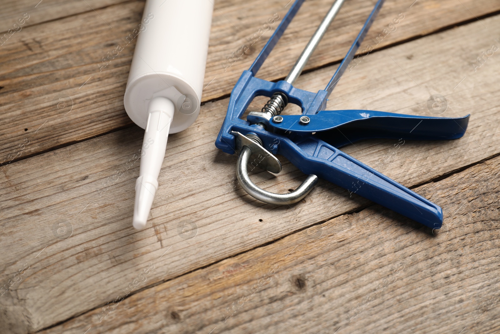 Photo of Glue gun and tube on wooden background, closeup