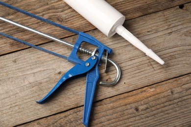 Photo of Glue gun and tube on wooden background, closeup