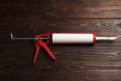 Photo of One glue gun on wooden background. Construction tool