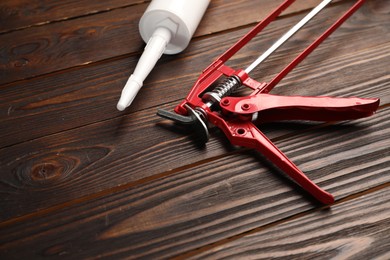 Photo of Glue gun and tube on wooden background, closeup