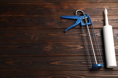 Photo of Glue gun and tube on wooden background, top view. Space for text