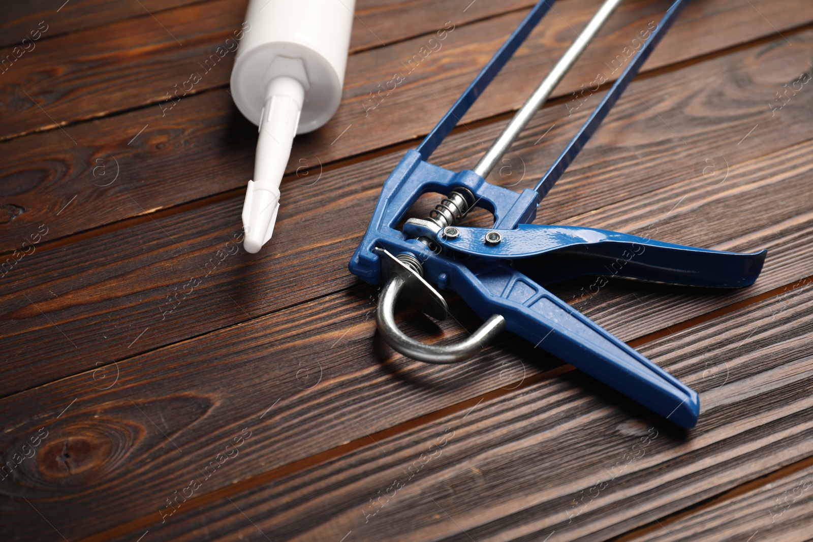 Photo of Glue gun and tube on wooden background, closeup