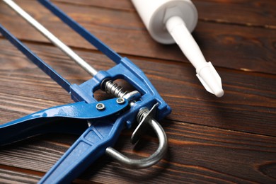 Glue gun and tube on wooden background, closeup