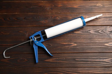 Photo of One glue gun on wooden background. Construction tool