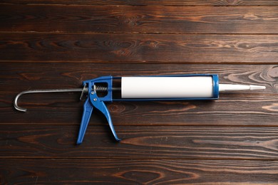 Photo of One glue gun on wooden background. Construction tool