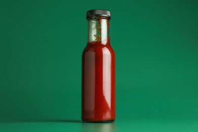 Photo of Tasty ketchup in bottle on green background