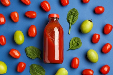 Photo of Tasty ketchup in bottle, tomatoes and basil on blue background, flat lay