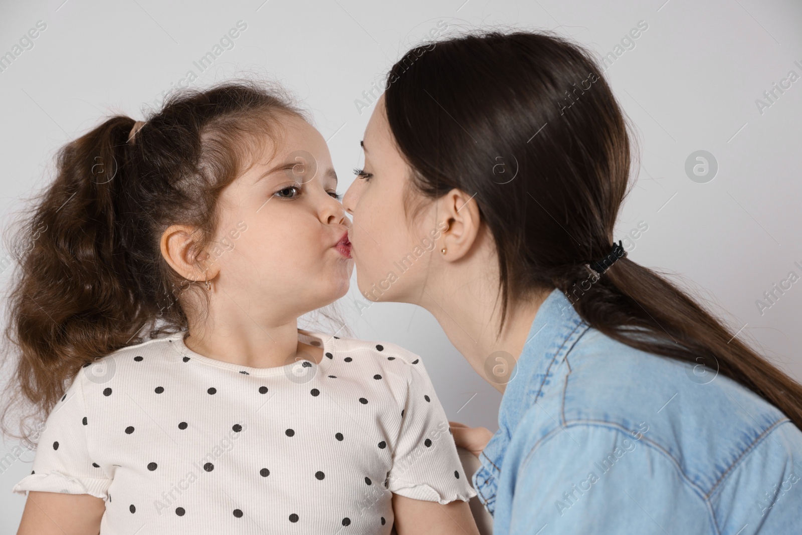 Photo of Cute little girl kissing her sister on white background