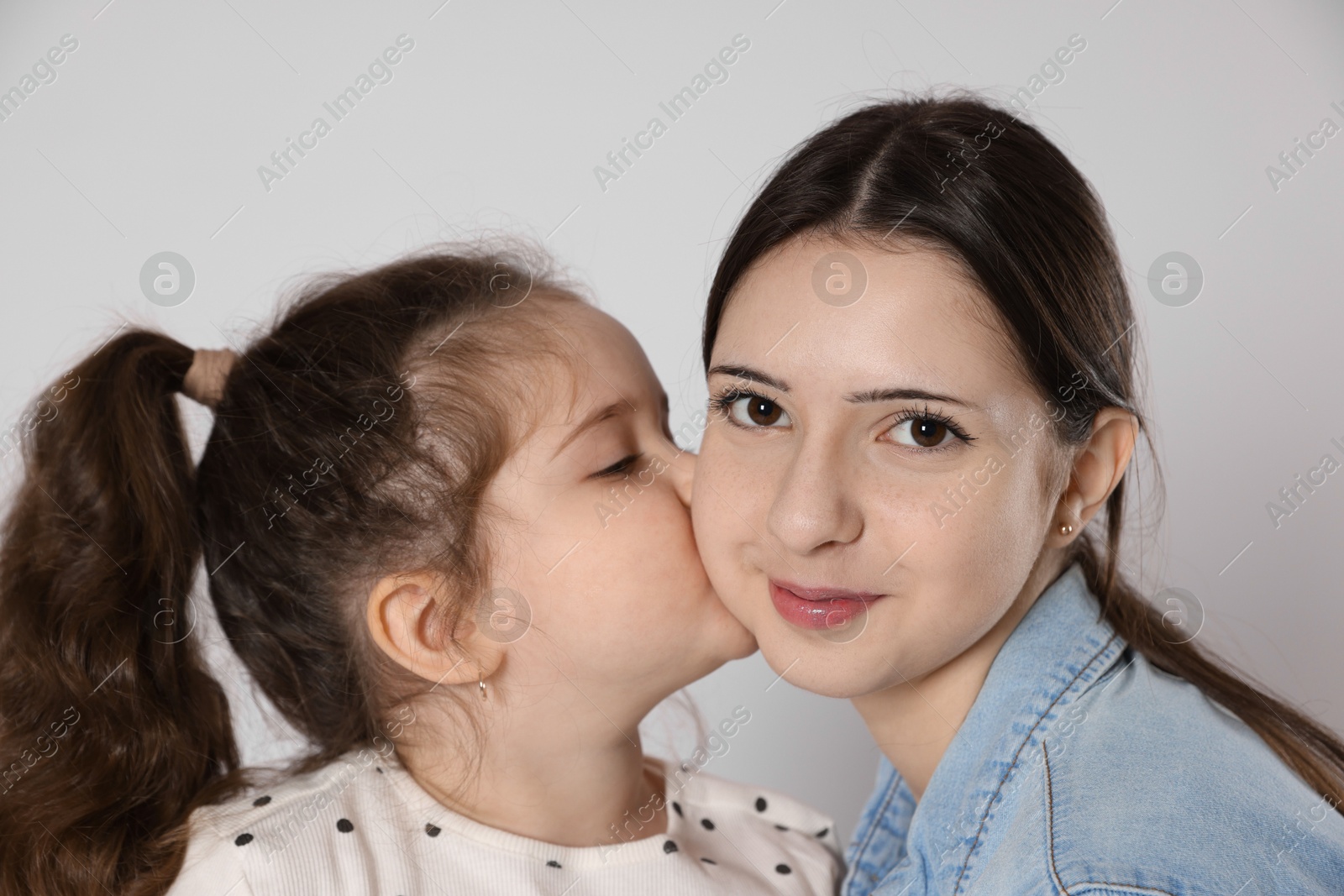 Photo of Cute little girl kissing her sister on white background