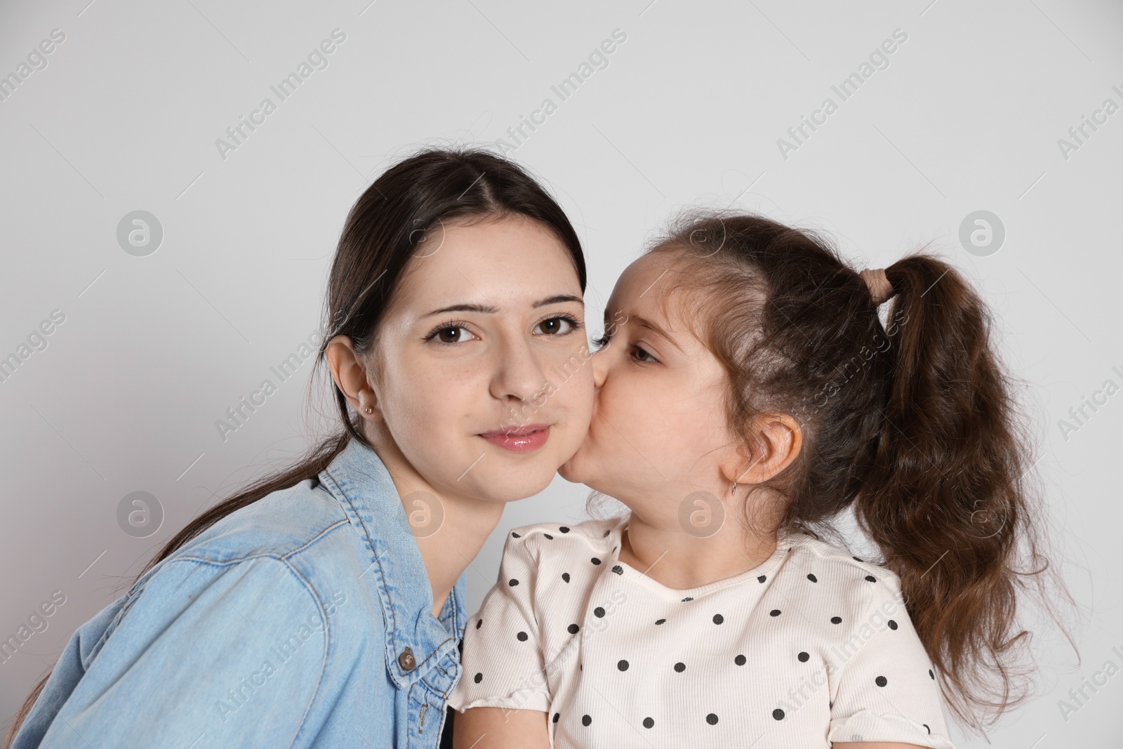 Photo of Cute little girl kissing her sister on white background