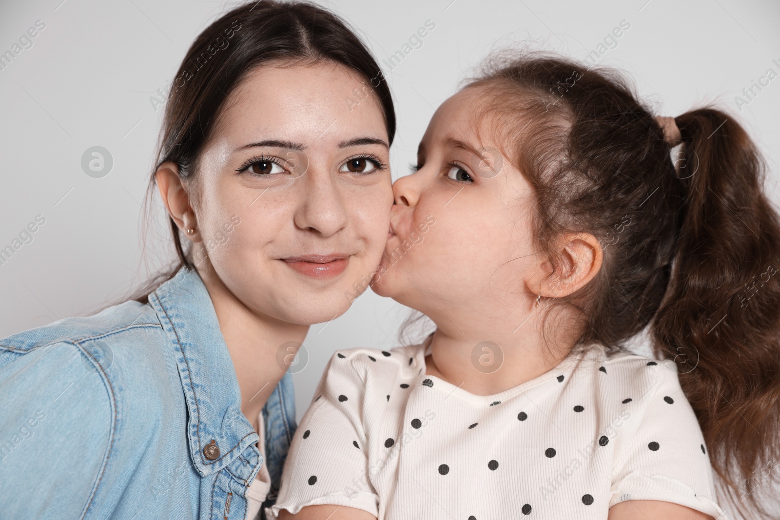 Photo of Cute little girl kissing her sister on white background