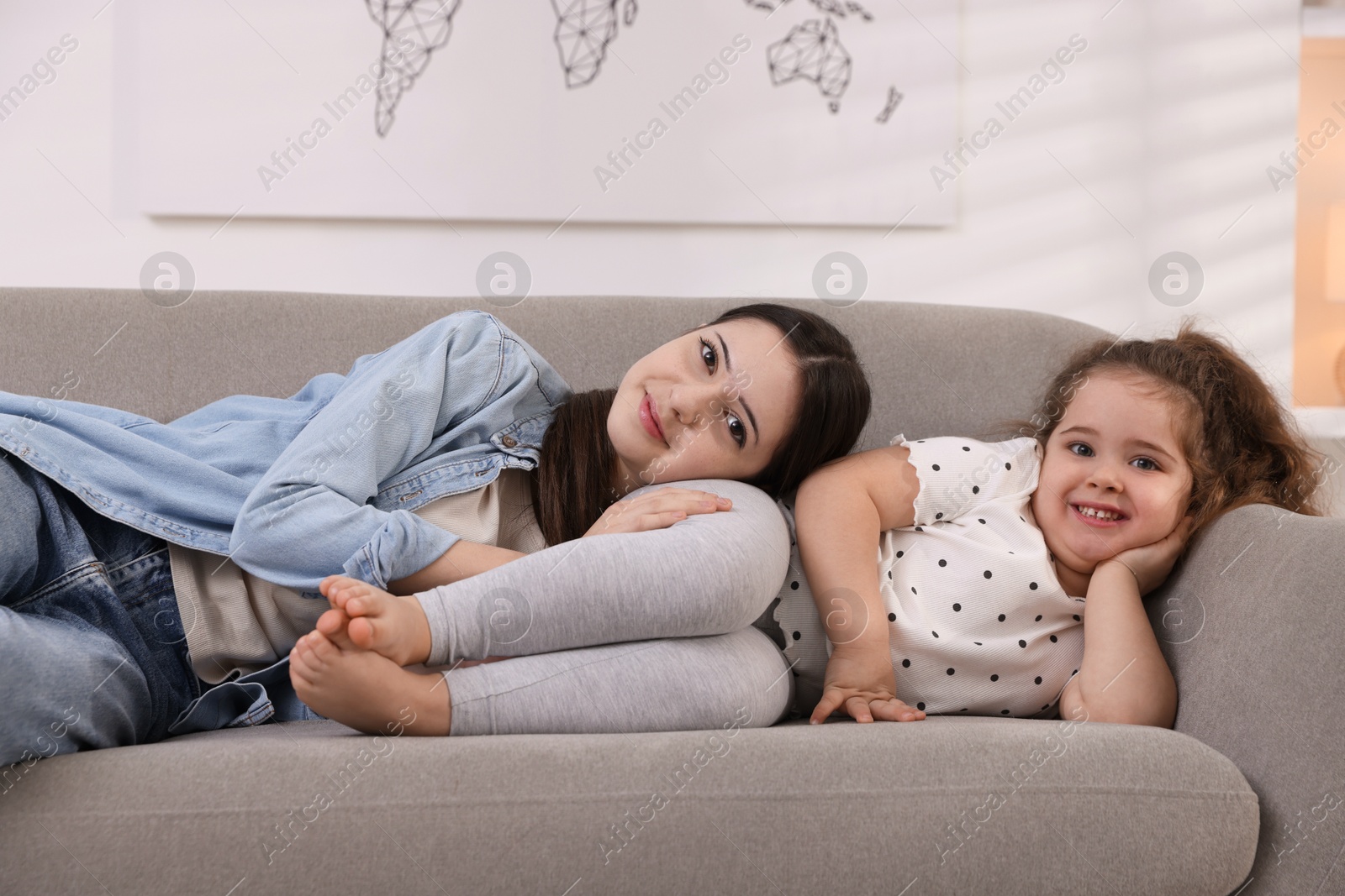 Photo of Cute little girl and her sister on sofa at home