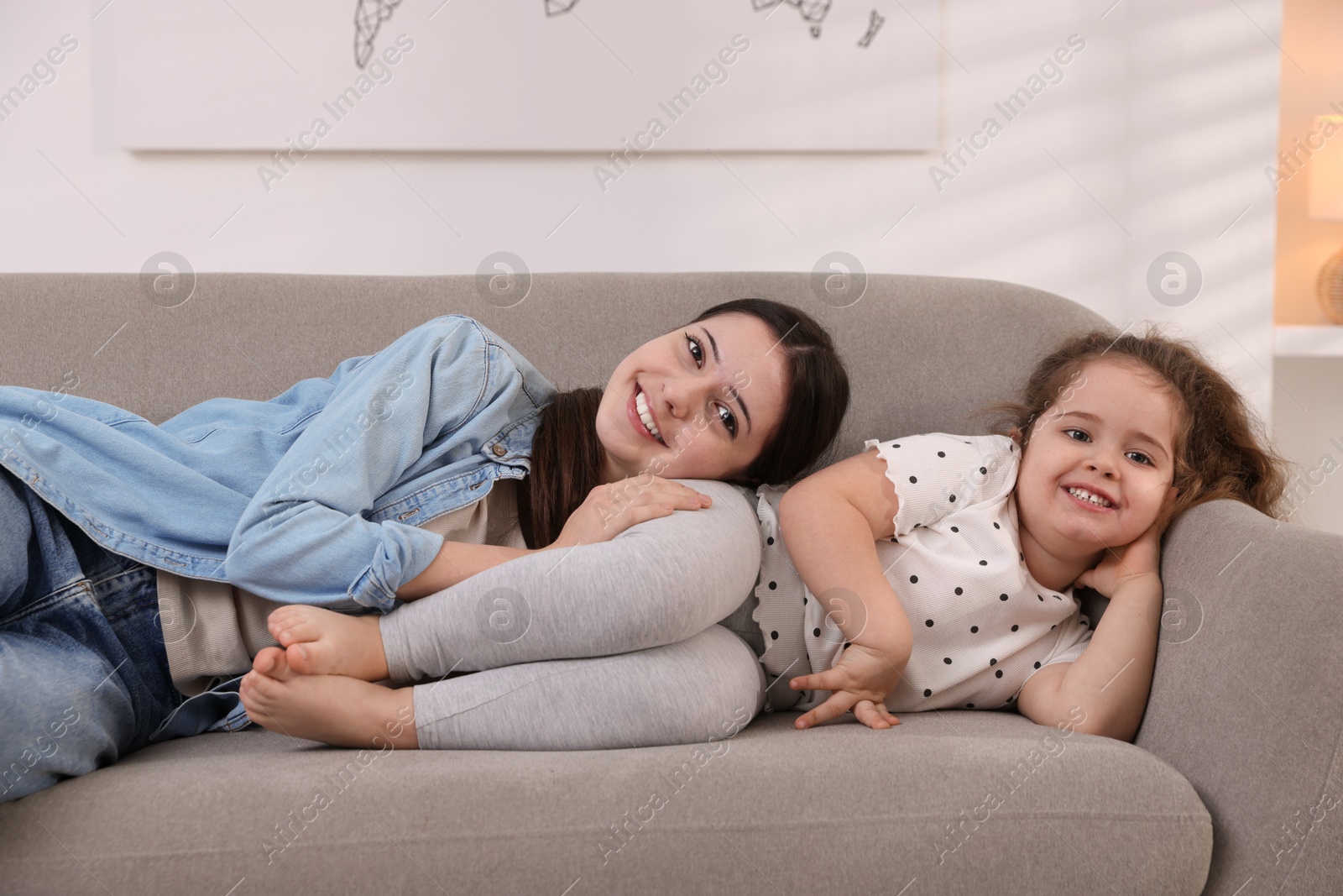 Photo of Cute little girl and her sister on sofa at home