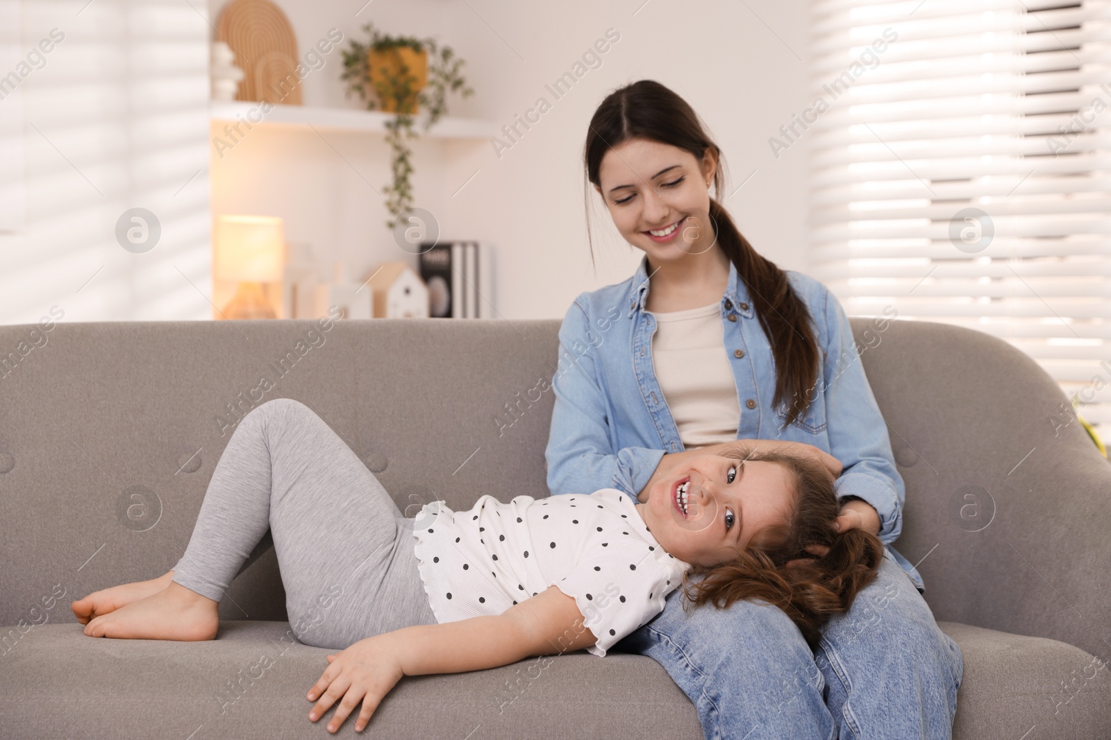 Photo of Cute little girl and her sister on sofa at home