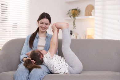 Photo of Cute little girl and her sister on sofa at home