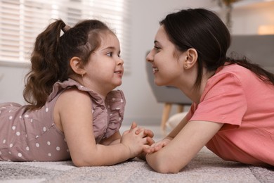 Photo of Cute little girl and her sister on rug at home