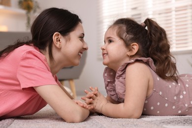 Photo of Cute little girl and her sister on rug at home