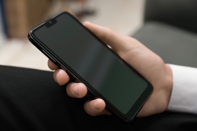 Photo of Man using smartphone with blank screen indoors, closeup