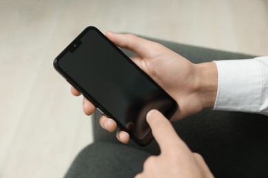 Photo of Man using smartphone with blank screen indoors, closeup