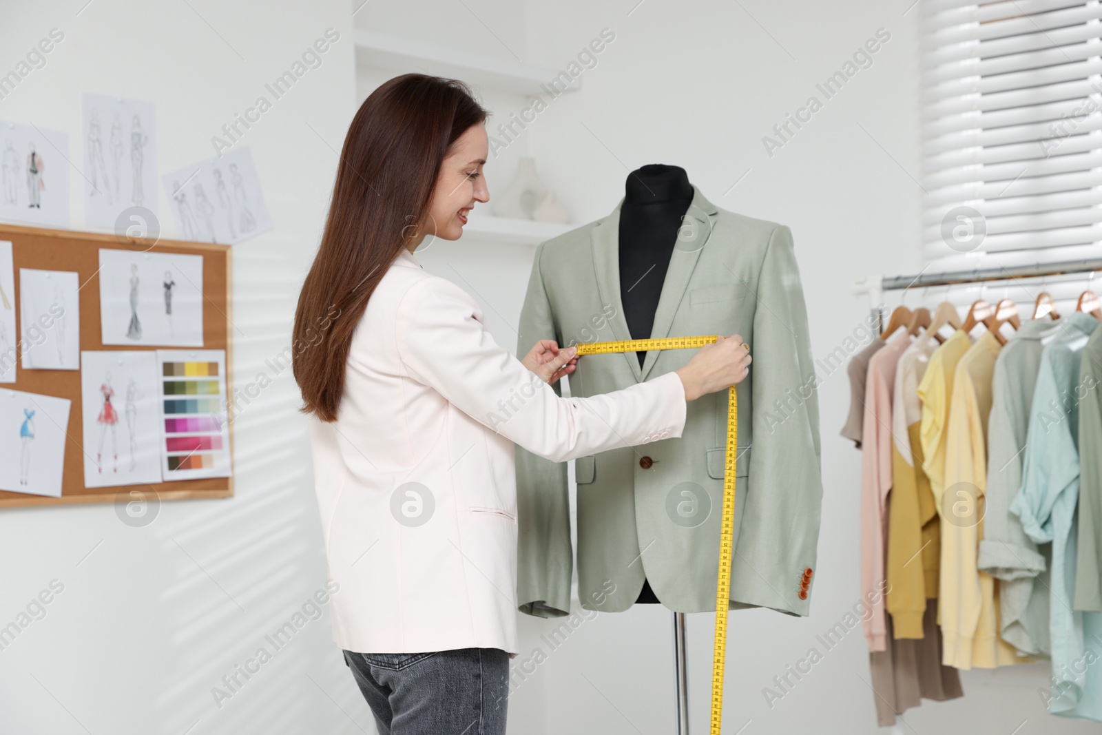 Photo of Fashion designer taking measurements of jacket in workshop