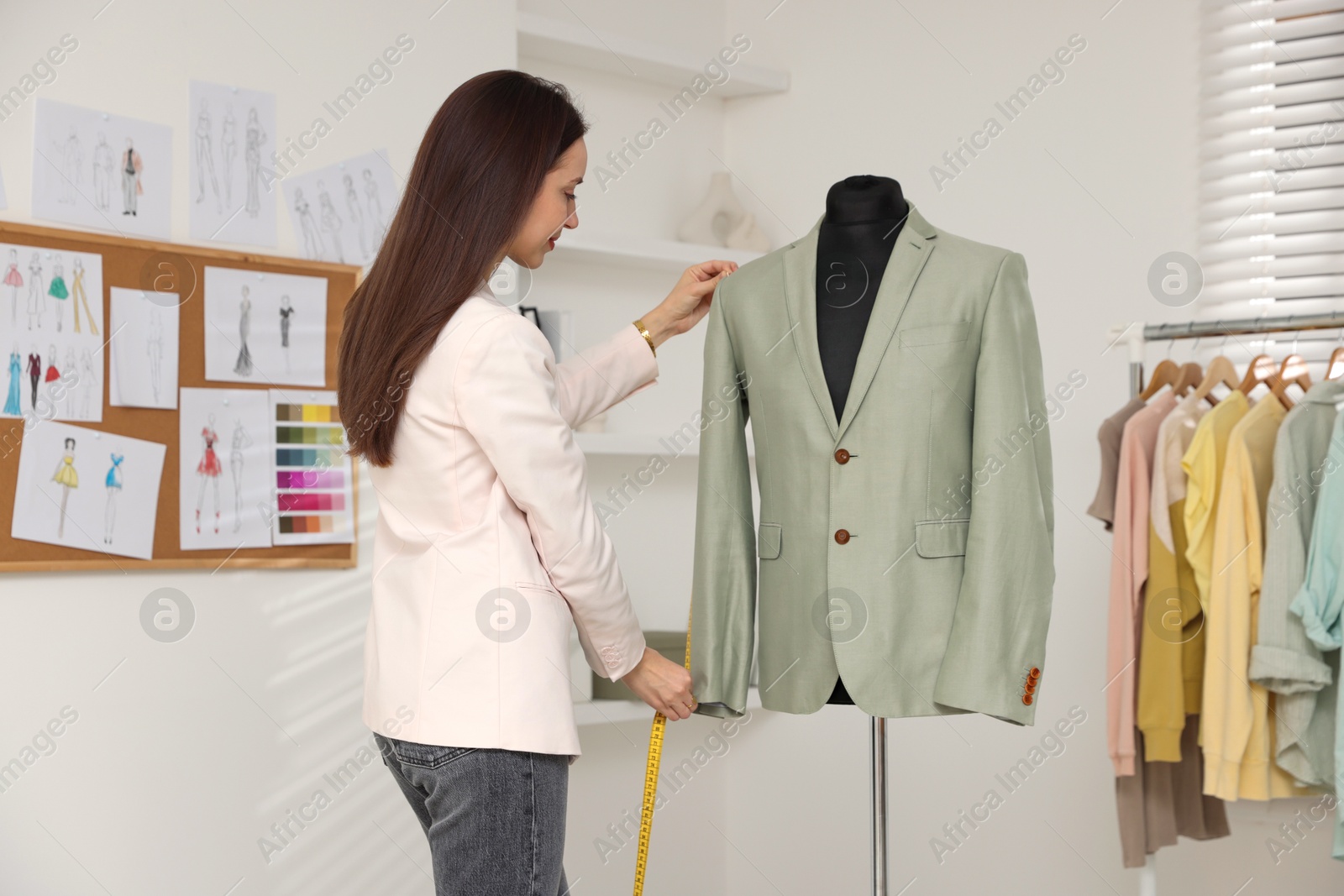 Photo of Fashion designer measuring jacket sleeve length in workshop