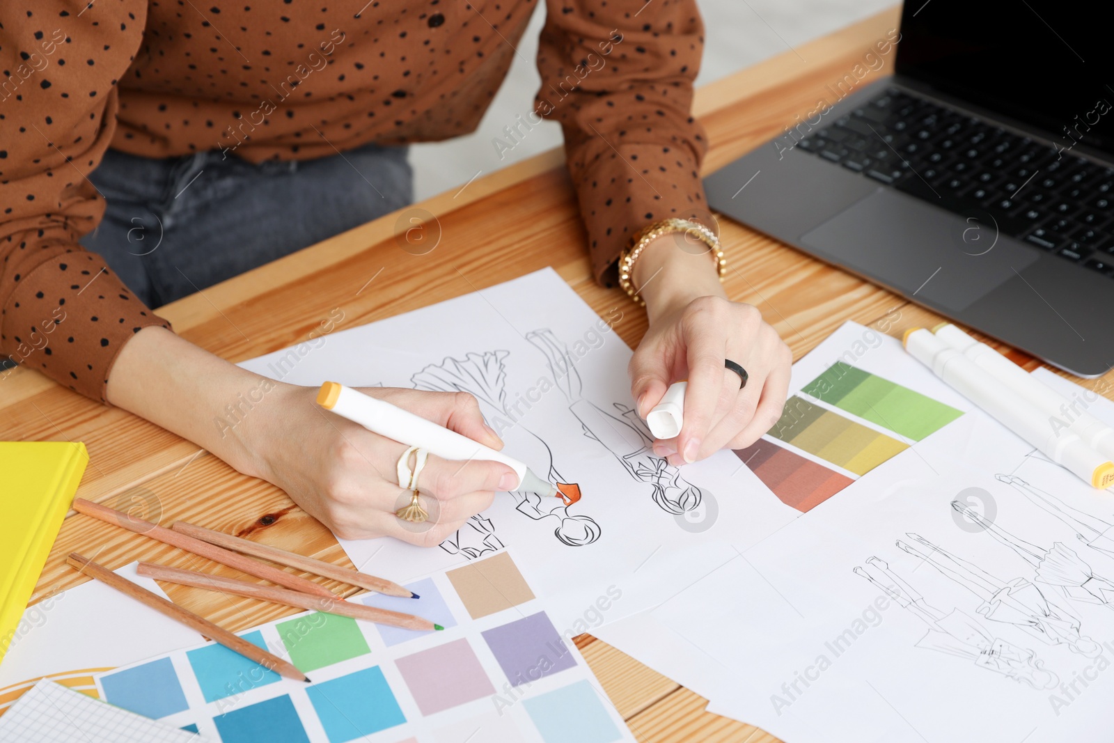 Photo of Fashion designer drawing sketch of clothes at wooden table in workshop, closeup