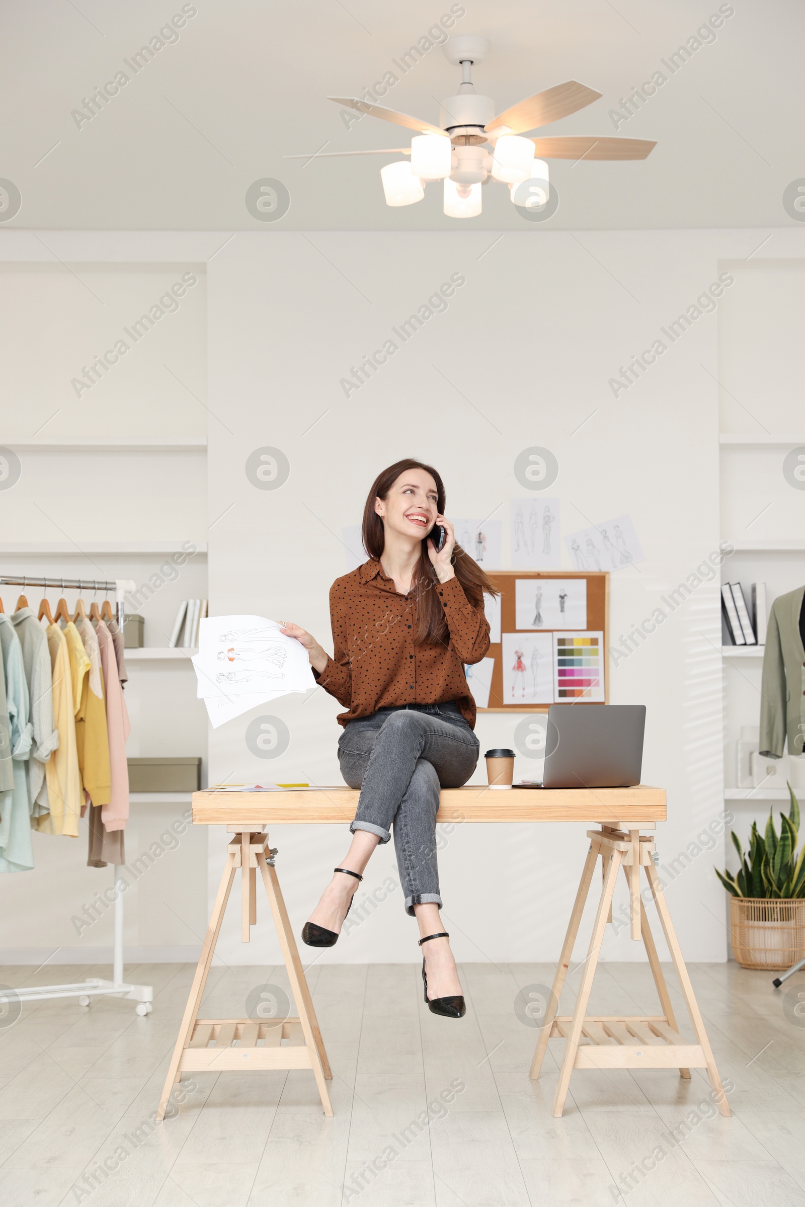 Photo of Fashion designer talking on smartphone in workshop