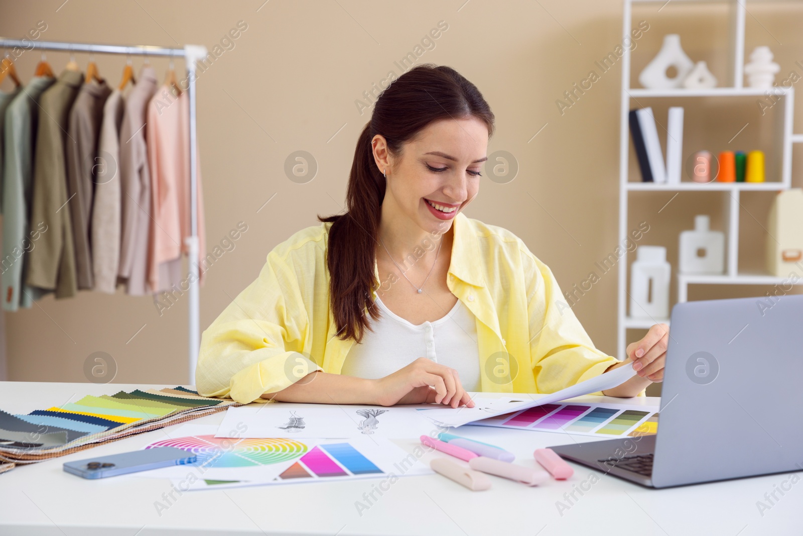 Photo of Fashion designer working at white table in workshop