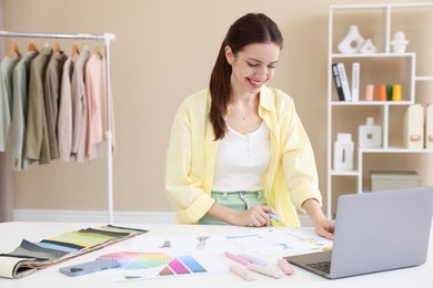 Photo of Fashion designer working at white table in workshop