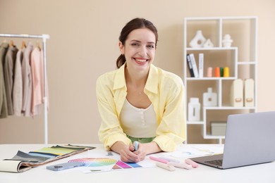 Photo of Fashion designer working at white table in workshop