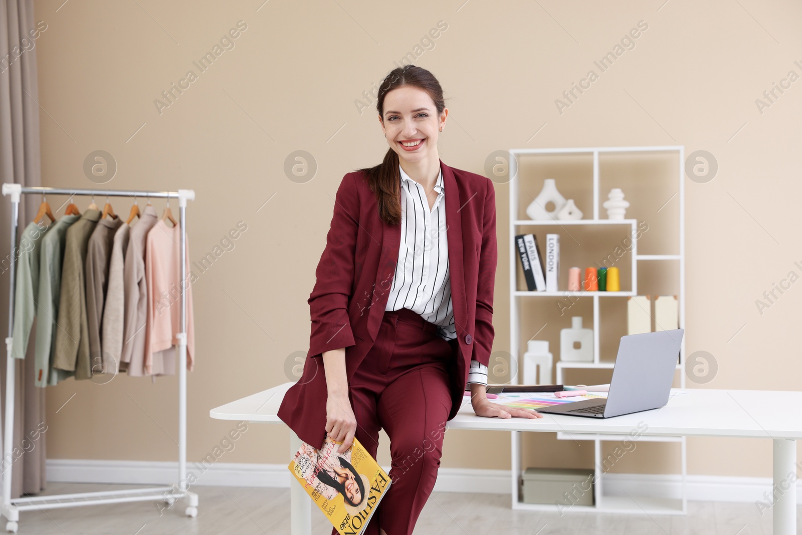 Photo of Fashion designer with magazine sitting on table in workshop