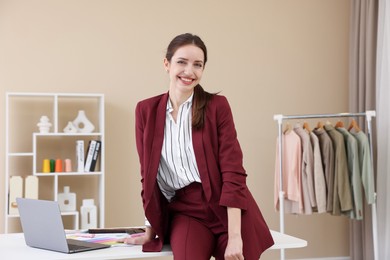 Photo of Fashion designer sitting on table in workshop