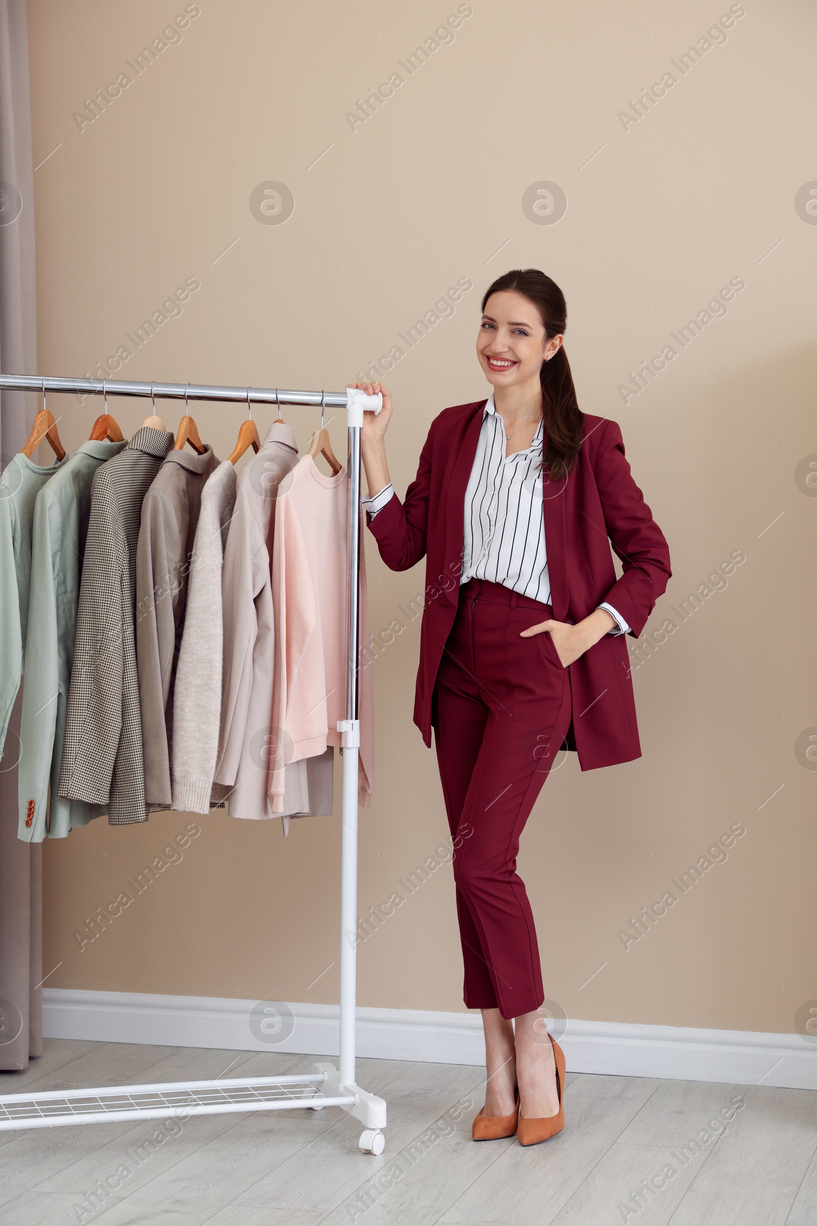 Photo of Fashion designer near rack with clothes in workshop