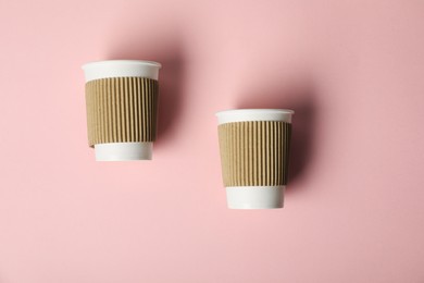 Photo of Paper cups on pink background, flat lay. Mockup for design