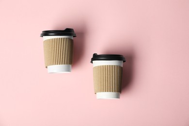 Photo of Paper cups with lids on pink background, flat lay. Mockup for design