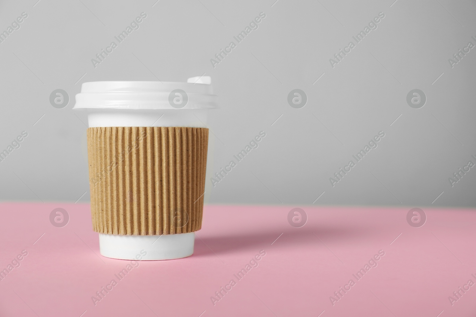 Paper cup with lid on pink table against grey background, closeup. Mockup for design Photo of Paper cup with lid on pink table against grey background, closeup. Mockup for design