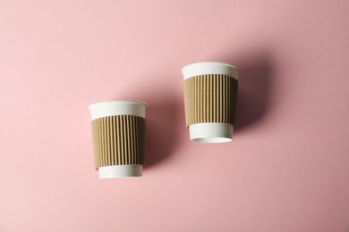Photo of Paper cups on pink background, flat lay. Mockup for design