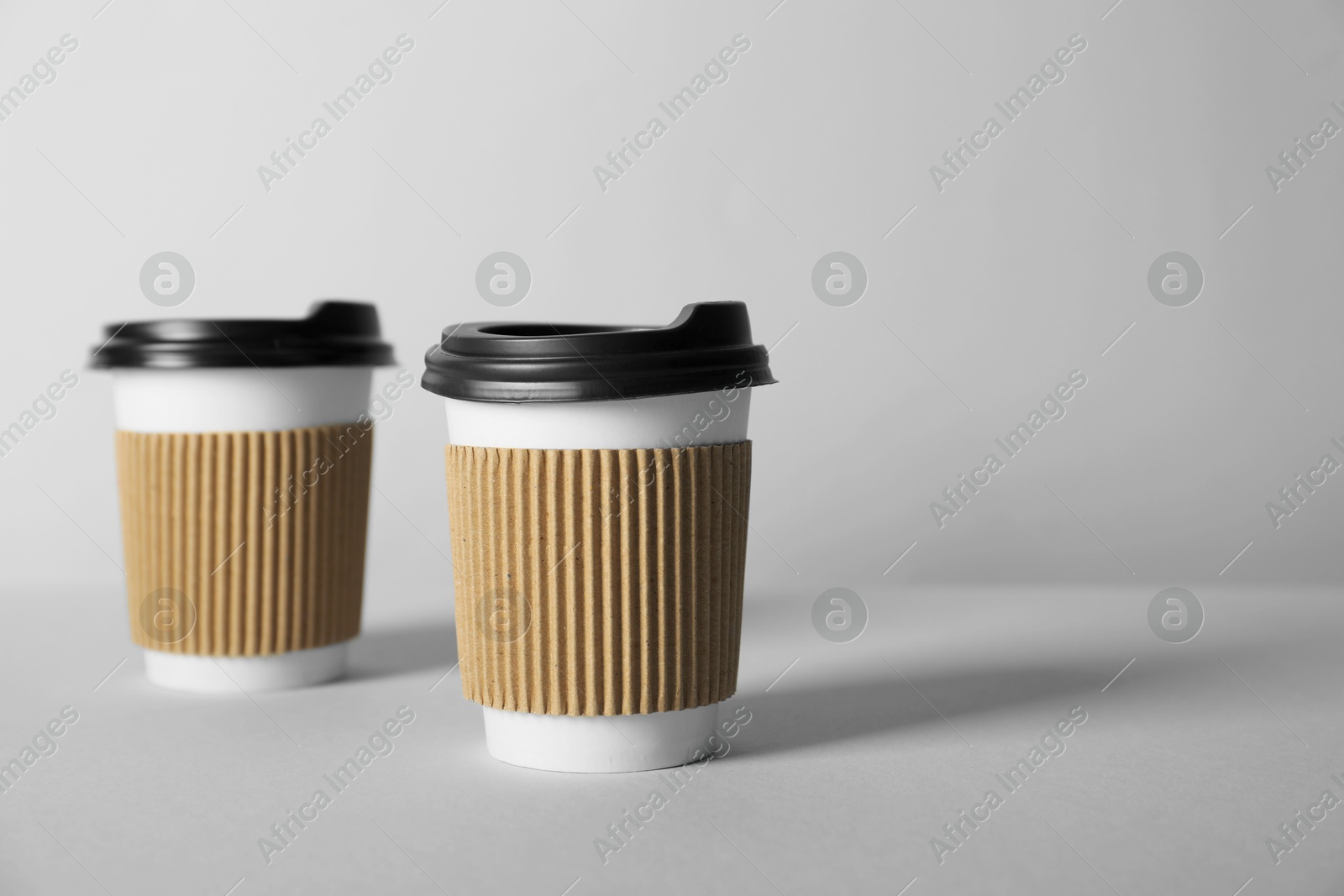 Paper cups with lids on grey background. Mockup for design Photo of Paper cups with lids on grey background. Mockup for design