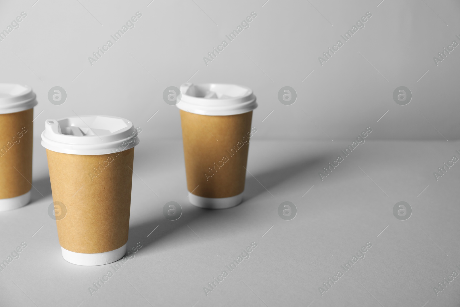 Paper cups with lids on grey background. Mockup for design Photo of Paper cups with lids on grey background. Mockup for design