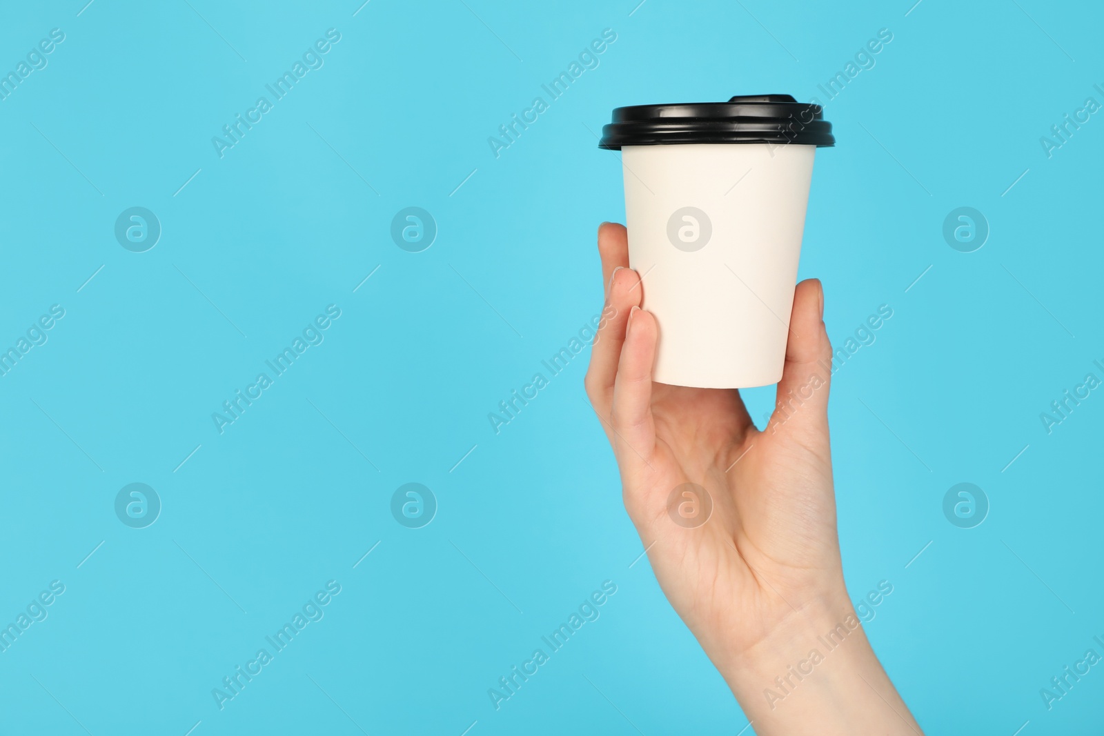 Woman holding paper cup on light blue background, closeup. Mockup for design Photo of Woman holding paper cup on light blue background, closeup. Mockup for design