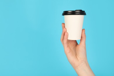 Photo of Woman holding paper cup on light blue background, closeup. Mockup for design