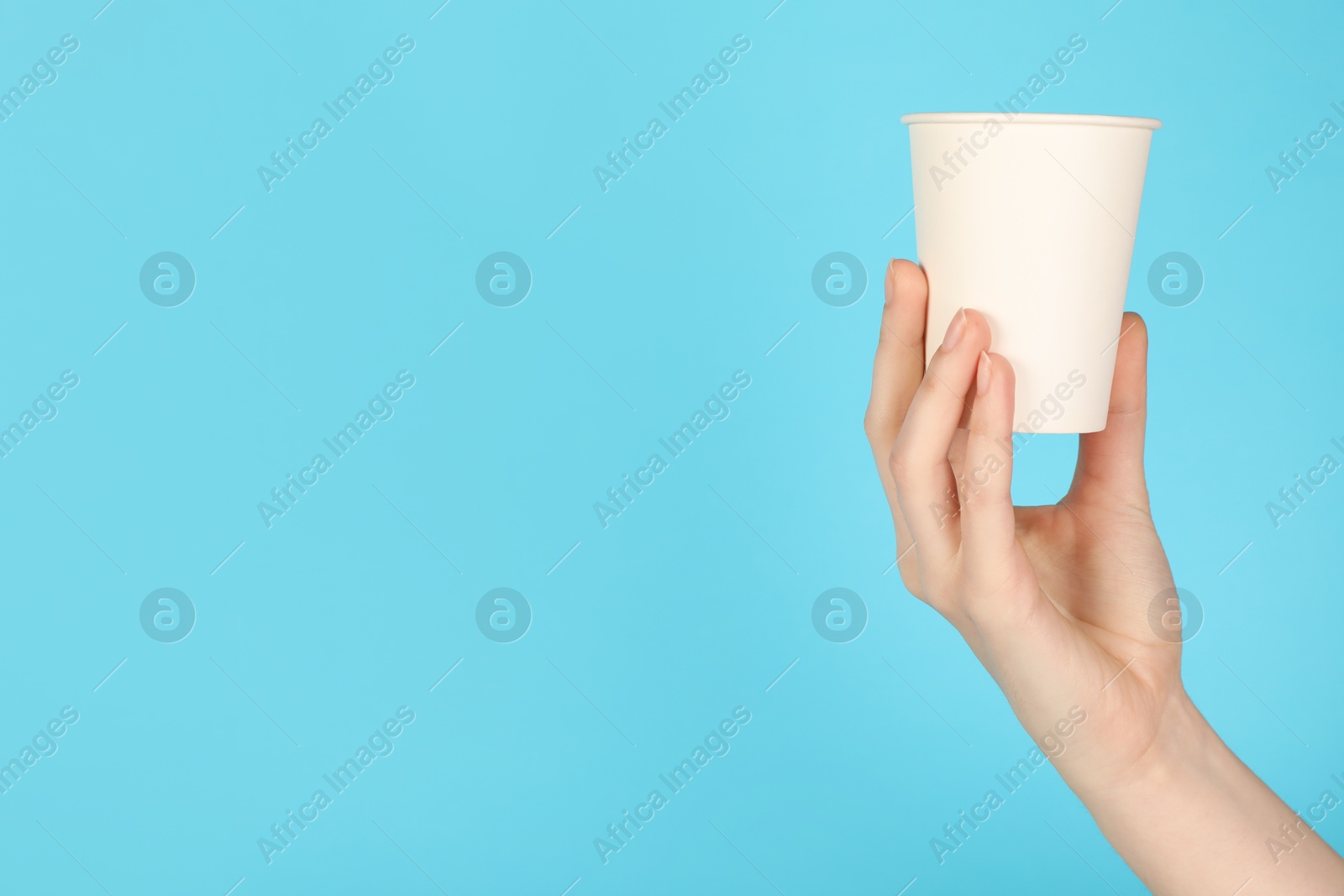 Woman holding paper cup on light blue background, closeup. Mockup for design Photo of Woman holding paper cup on light blue background, closeup. Mockup for design