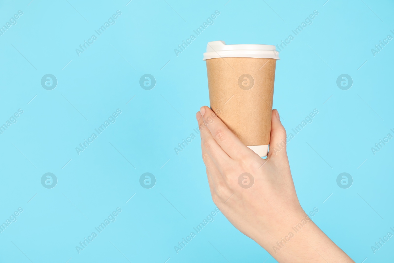 Woman holding paper cup on light blue background, closeup. Mockup for design Photo of Woman holding paper cup on light blue background, closeup. Mockup for design