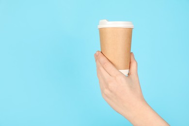 Photo of Woman holding paper cup on light blue background, closeup. Mockup for design