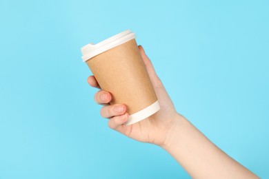 Photo of Woman holding paper cup on light blue background, closeup. Mockup for design
