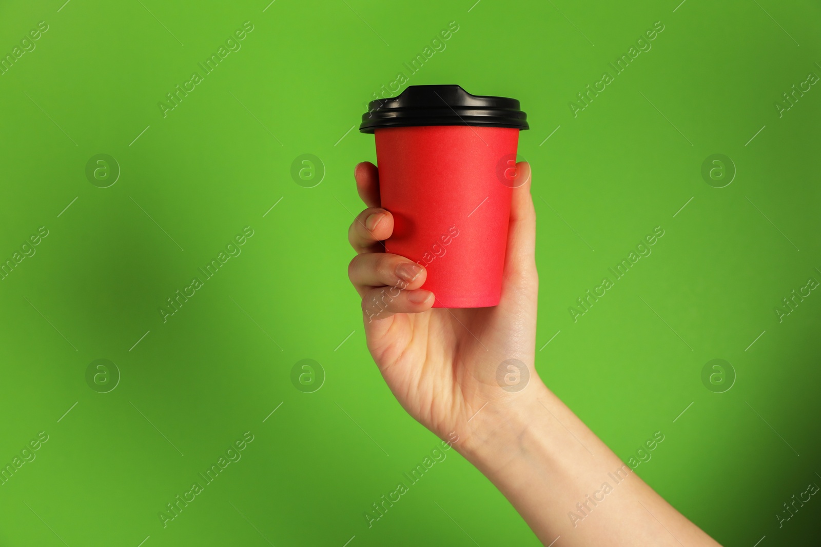 Woman holding paper cup on green background, closeup. Mockup for design Photo of Woman holding paper cup on green background, closeup. Mockup for design