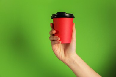 Photo of Woman holding paper cup on green background, closeup. Mockup for design