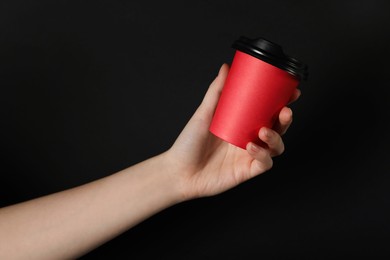 Photo of Woman holding paper cup on black background, closeup. Mockup for design