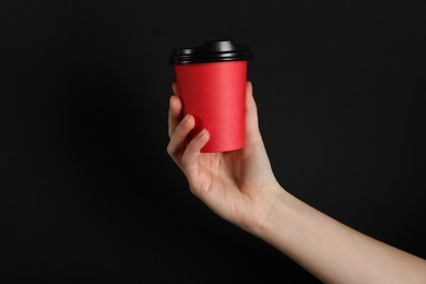 Photo of Woman holding paper cup on black background, closeup. Mockup for design